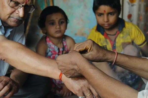 cropped image person tying thread man hand while children looking home