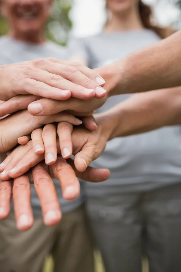happy volunteer family putting their hands together